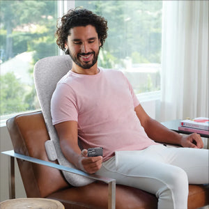 Man sitting on the couch using the Homedics® Ultra Slim Shiatsu Massage Cushion with Heat