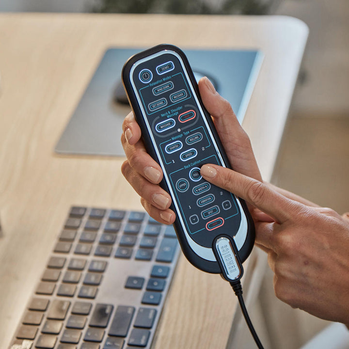 Close-up view of hand holding the controller for the Homedics 2-in-1 Shiatsu Massage Cushion and Cordless Body Massager