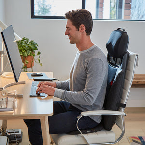 Man sits at computer desk and types on laptop while enjoying a massage from the Homedics 2-in-1 Shiatsu Massage Cushion and Cordless Body Massager