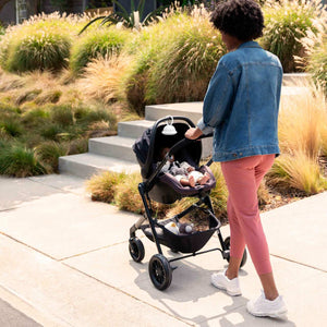 Woman pushes stroller down street as baby enjoys sounds from the Homedics SoundSpa On-The-Go