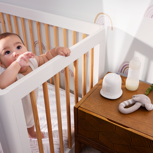 Baby roams in crib with Homedics SoundSpa Lullaby with Sounds & Projection on nightstand