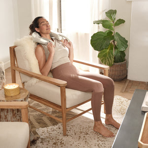 Woman leans back in chair while enjoying her Homedics Shiatsu Rechargeable Neck Massager with Heat