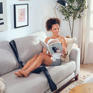 Woman stretched out on couch enjoys calf massage using the Homedics Shiatsu Neck and Body Massager with Heat