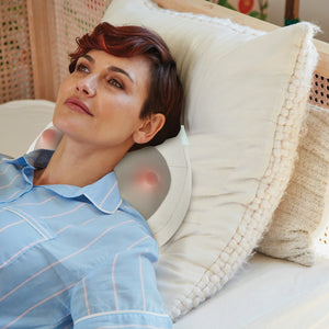Woman laying on bed enjoys neck massage from the Homedics Total Recline Neck Massager