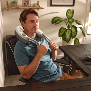 A man sits down on a chair wearing the Pro Therapy Vibration Neck Massager with Soothing Heat on his shoulders