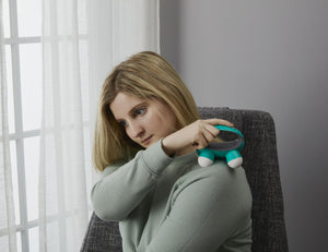 Woman enjoys shoulder massage using the Homedics Quatro Mini Massager