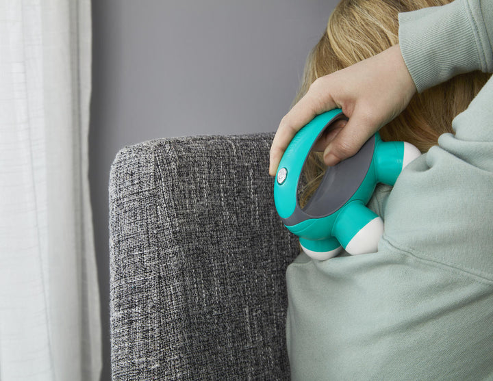 Woman massages upper back with the Homedics Quatro Mini Massager