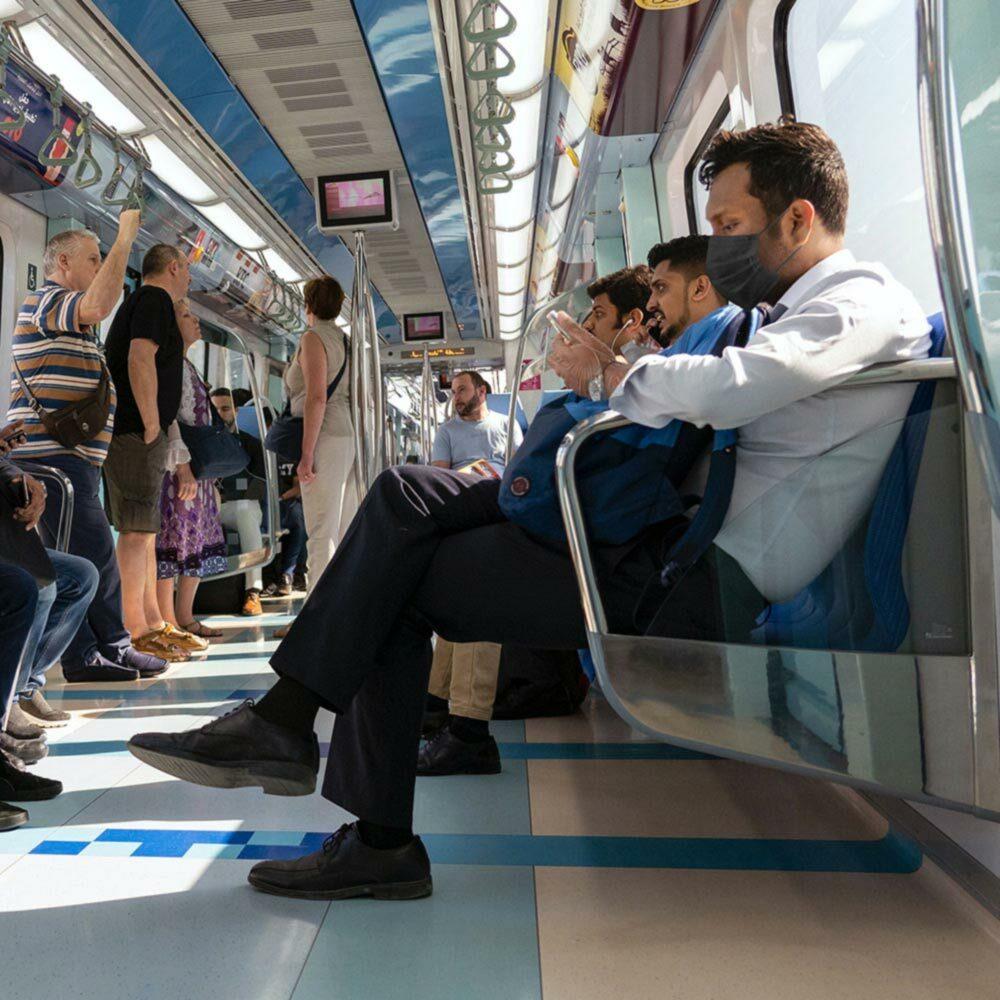 Man sits on train while wearing a Homedics Black Single Use Ear-Loop Face Mask (50 Count)