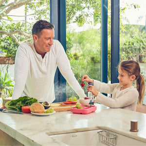 Child sprays strawberry with the Homedics Ozone Clean Multipurpose Cleaner while man watches