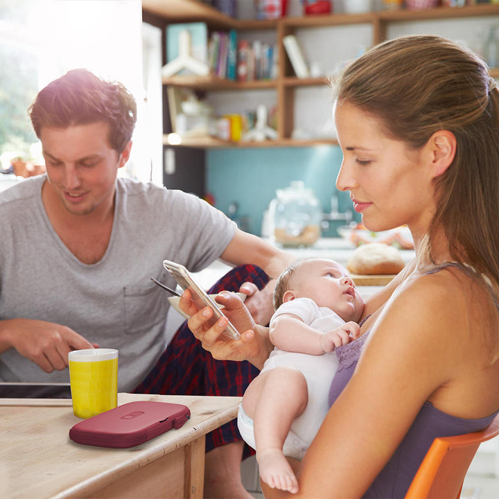 Red | Woman holds baby at table next to man with the Homedics UV CLEAN Portable Phone Sanitizer on table