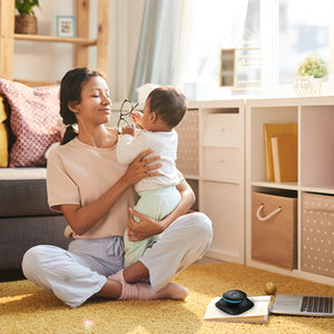 Woman holds baby with UV-Clean Portable Sanitizer Wand sitting on book