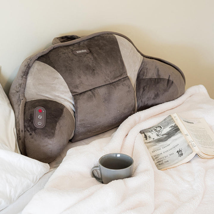Homedics Shiatsu Bedrest Plus on bed next to mug and open book