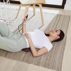 Woman lays on the Homedics Lumbar Lift Lower Back Stretcher and Massager on the floor while enjoying a lower back massage