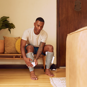 man sitting putting on his Homedics Real Relief Calf Compression Massager