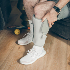 Man inserts universal battery in the Homedics® Modulair Compression Calf Wrap he is wearing