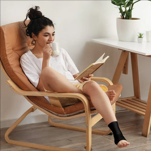 A woman sitting on a chair, having leisure time using the Homedics Hot and Cold Relief Gel Ankle Sleeve