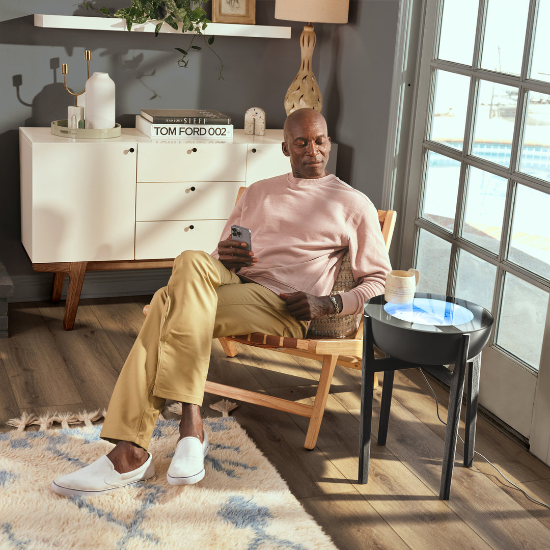 Walnut | drift 16" wood stand displays the drift sand table next to a man while he relaxes in the afternoon