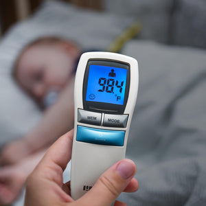 Top-down view of the Homedics Non-Contact Infrared Thermometer with sleeping baby in background