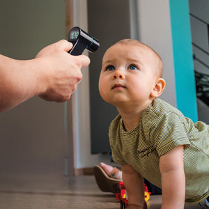Black | Person takes forehead temperature reading from baby using the black Homedics Infrared Ear and Forehead Thermometer in black