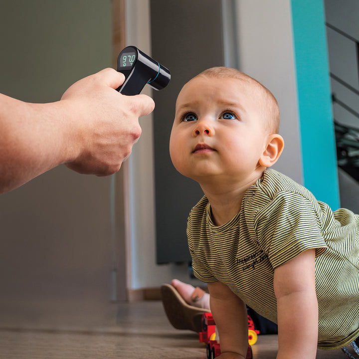 Black | Person takes forehead temperature reading from baby using the black Homedics Infrared Ear and Forehead Thermometer in black