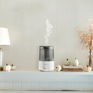 Homedics TotalComfort Adjustable Mist Ultrasonic Humidifier sitting on table spraying mist