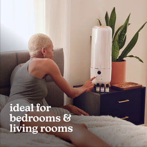 Woman in bed turning on Homedics TotalComfort® Deluxe Large Room Ultrasonic Humidifier.