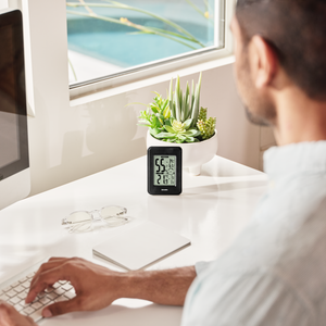 Over the shoulder view of man sitting at desk looking at Homedics Indoor Humidity Monitor