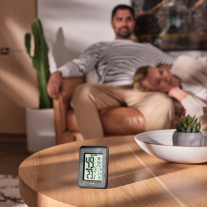 Homedics Indoor Humidity Monitor sits on living room table as couple sits on couch