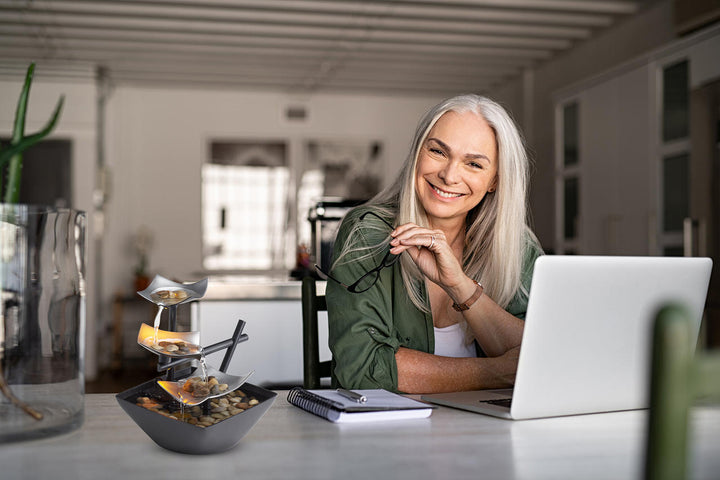Woman smiling with Homedics EnviraScape Silver Springs Relaxation Fountain on desk