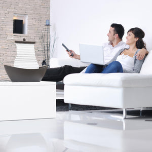 Couple sits on white couch near a Homedics White Waters Relaxation Fountain