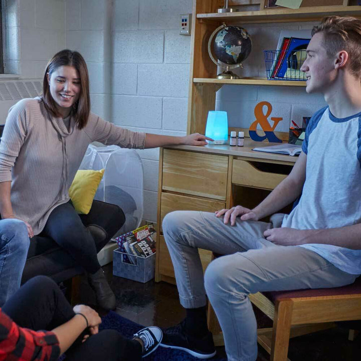 Group sits around Homedics Connect Ultrasonic Aroma Diffuser on dorm room dresser