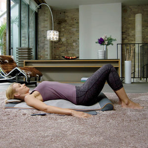 Woman laying on Homedics Air Compression Back Stretching Mat in living room