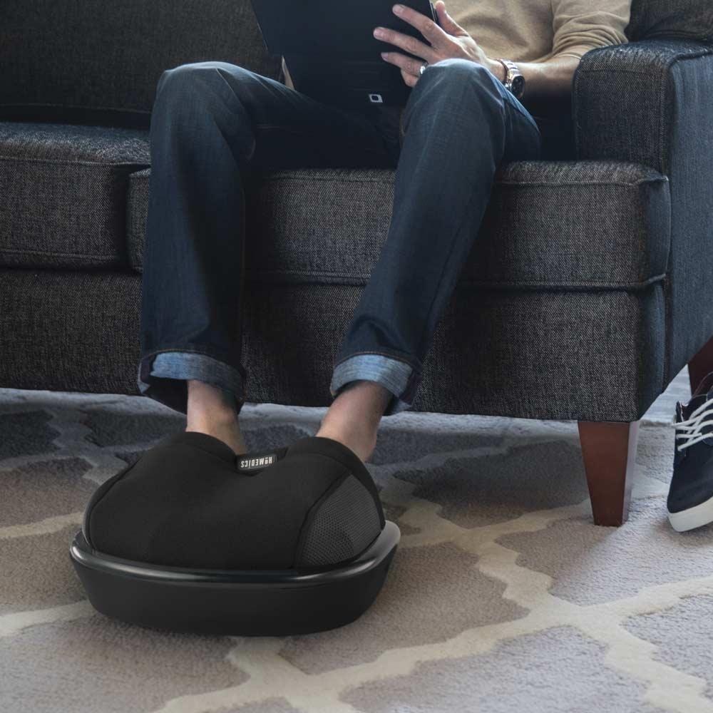 Man sits on couch and enjoys a foot massage from the Homedics Shiatsu Air Max Foot Massager with Heat
