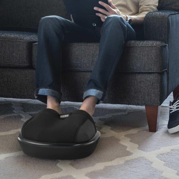 Man sits on couch and enjoys a foot massage from the Homedics Shiatsu Air Max Foot Massager with Heat