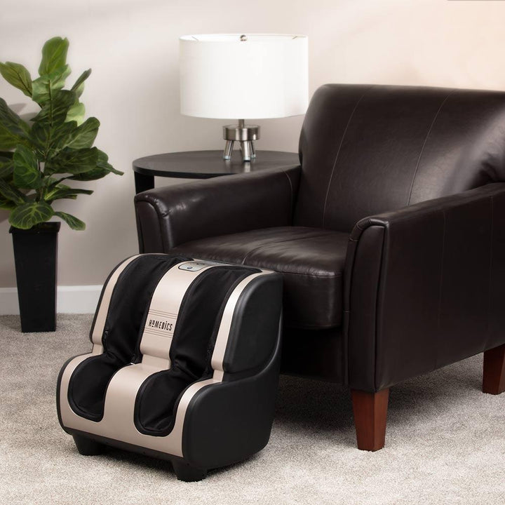 Angled view of the Homedics Therapist Select 2.0 Foot and Calf Massager with Soothing Heat on floor in front of chair