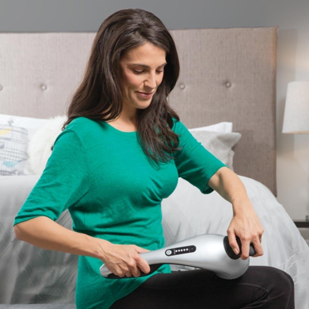 Woman uses the Homedics Cordless Pro Performance Percussion Massager for leg massage