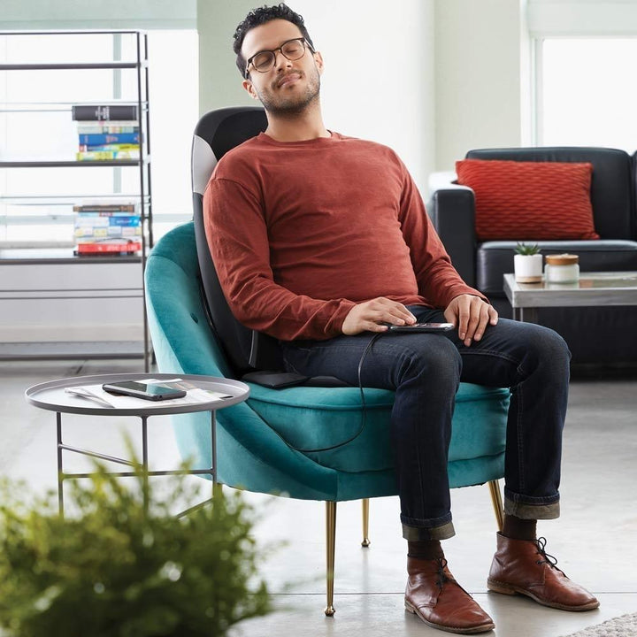 Man relaxes in chair while enjoying a massage from the Homedics 8-Node Shiatsu Plus Massage Cushion with Soothing Heat