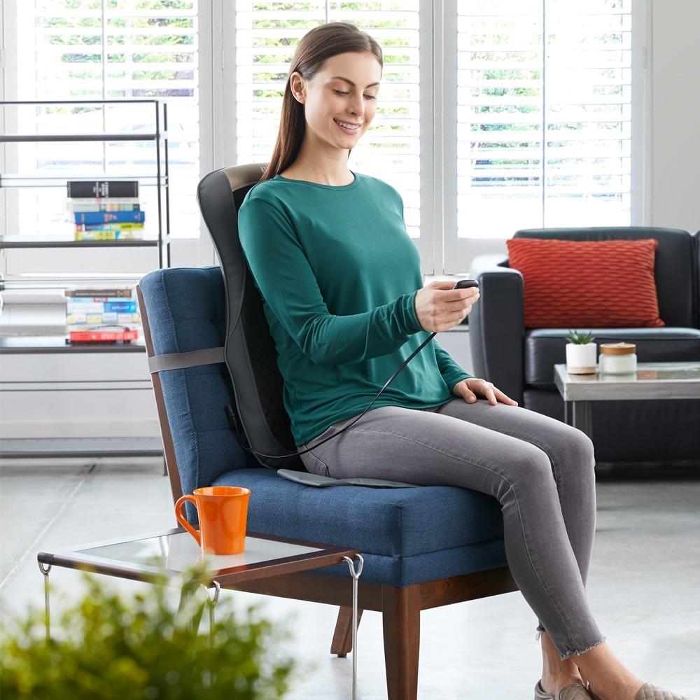 Woman sits on Homedics Cordless Shiatsu Pro+ Massage Cushion with Soothing Heat attached to chair
