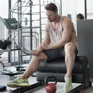 Man checks pulse with the Homedics Premium Pulse Oximeter during workout at gym