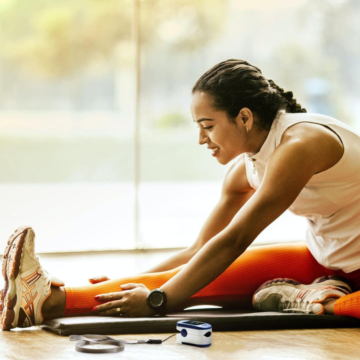 Woman stretches on floor next to the Homedics ACCARE Pulse Oximeter