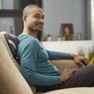 Man sits back on couch and enjoys a shoulder massage using the Homedics Gentle Touch Gel Cordless Massager with Heat