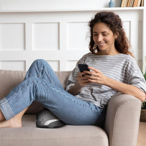 Woman relaxing on couch while enjoying a leg massage with theHomedics Gentle Touch Gel Cordless Massager with Heat