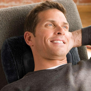Man lays back in reclining chair while enjoying neck massage from the Homedics Shiatsu Massage Pillow with Soothing Heat