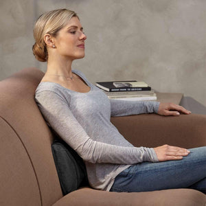 Woman relaxes on couch while enjoying lower back massage from the Homedics Shiatsu Massage Pillow with Soothing Heat