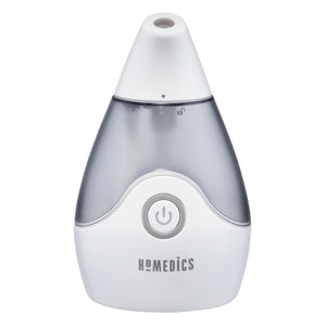 Woman smiles while looking at Homedics TotalComfort Personal Ultrasonic Humidifier on table